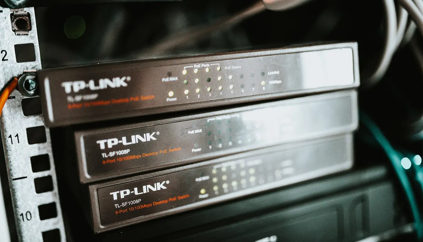 Network switches arranged in a server rack with visible LED lights indicating connection status and power levels